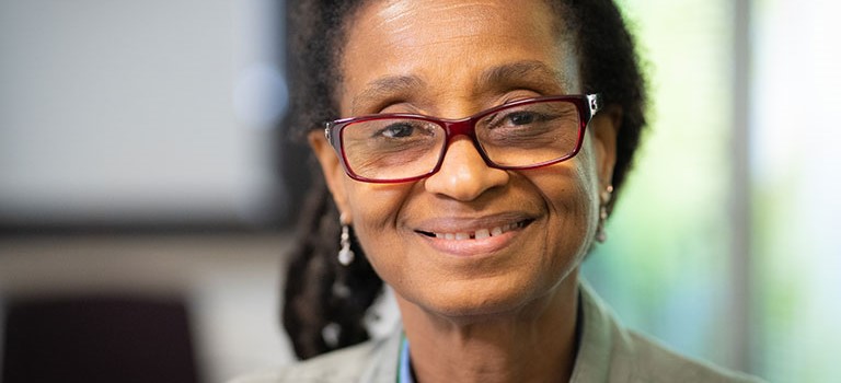 Woman with short brown hair, glasses and earrings smiling at the camera